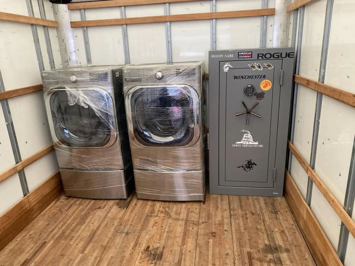 Safe and shrink-wrapped washer and dryer secured inside an M.C. Movers truck